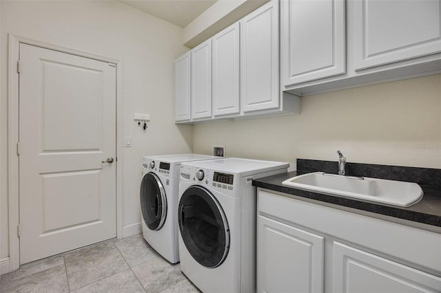 laundry area featuring washer and dryer, light tile patterned flooring, cabinet space, a sink, and baseboards