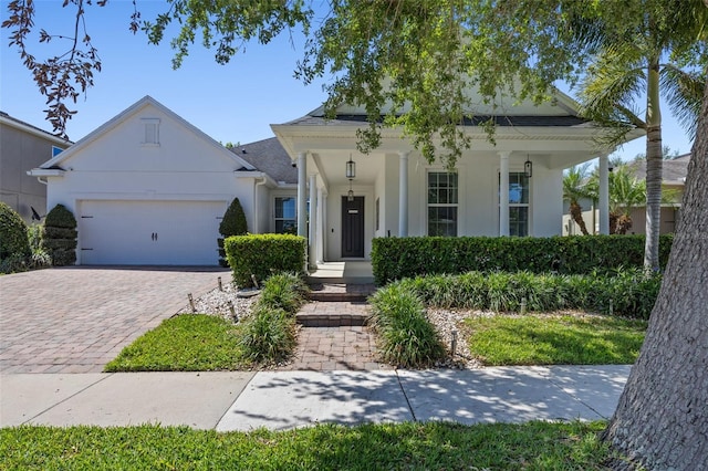 view of front of home featuring covered porch, stucco siding, driveway, and a garage