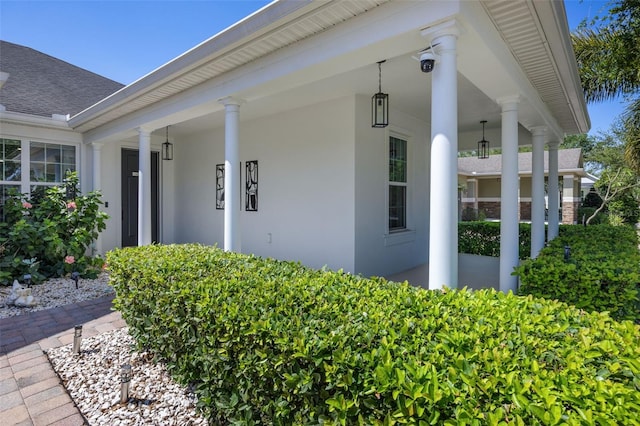 view of exterior entry with covered porch and stucco siding