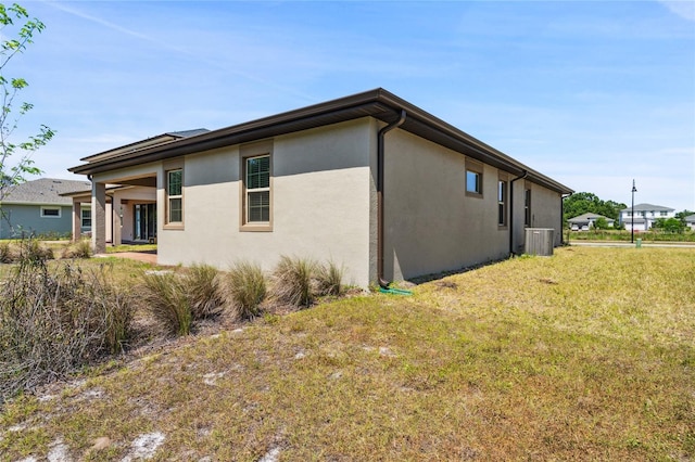 3128 Oxbow Ct, Harmony, FL 34773 - view of side of home with central air condition unit, stucco siding, and a yard
