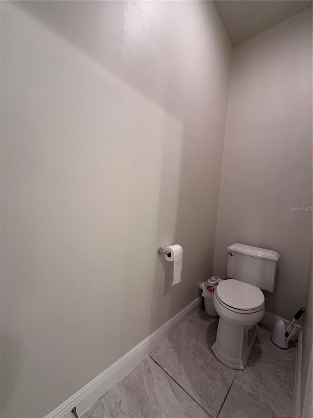 bathroom featuring toilet, baseboards, and marble finish floor