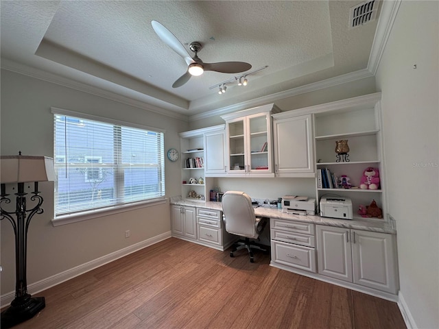 office space featuring a raised ceiling, a textured ceiling, ceiling fan, and built in study area