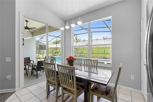 dining area featuring a ceiling fan, light tile patterned floors, a sunroom, and a healthy amount of sunlight