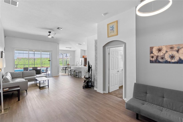 living area featuring baseboards, ceiling fan, visible vents, and wood finished floors