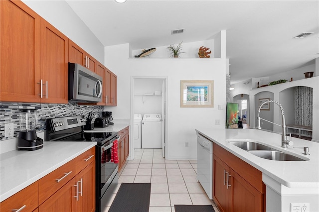 kitchen with visible vents, washing machine and clothes dryer, tasteful backsplash, a sink, and appliances with stainless steel finishes