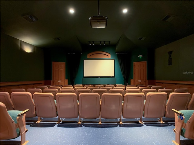 cinema room featuring visible vents, rail lighting, and wainscoting