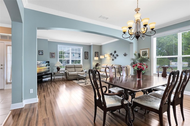 dining room with an inviting chandelier, arched walkways, wood finished floors, and visible vents