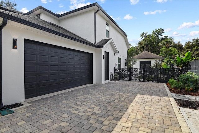 1840 Bryan Ave, Winter Park, FL 32789 - view of side of home featuring an attached garage, decorative driveway, stucco siding, and fence