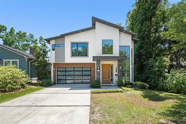 modern home with a garage, stucco siding, a front yard, and concrete driveway