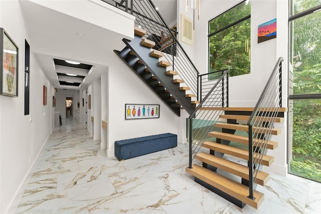 staircase with baseboards, plenty of natural light, and marble finish floor