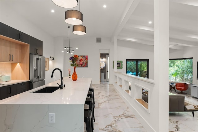kitchen featuring dark cabinets, a sink, marble finish floor, and high end refrigerator