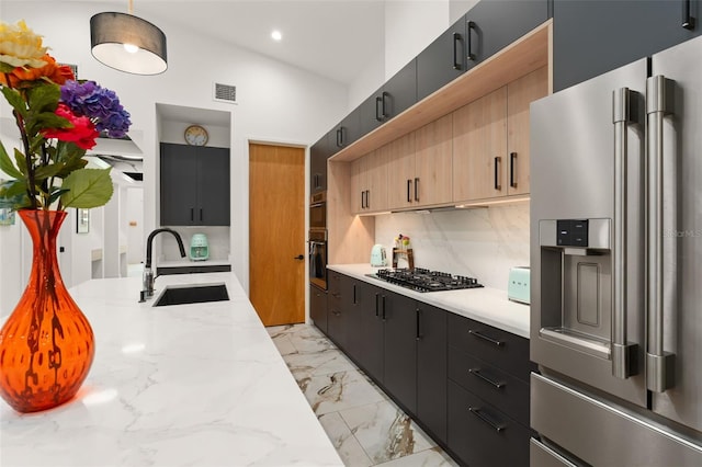 kitchen featuring visible vents, tasteful backsplash, a sink, dark cabinetry, and stainless steel appliances