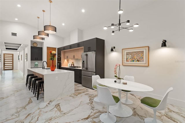 kitchen featuring high end fridge, dark cabinetry, light countertops, gas stovetop, and visible vents