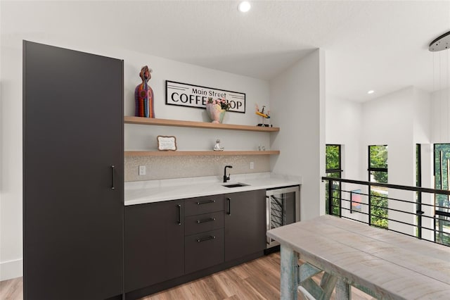 bar featuring a sink, indoor wet bar, beverage cooler, light wood-style floors, and recessed lighting