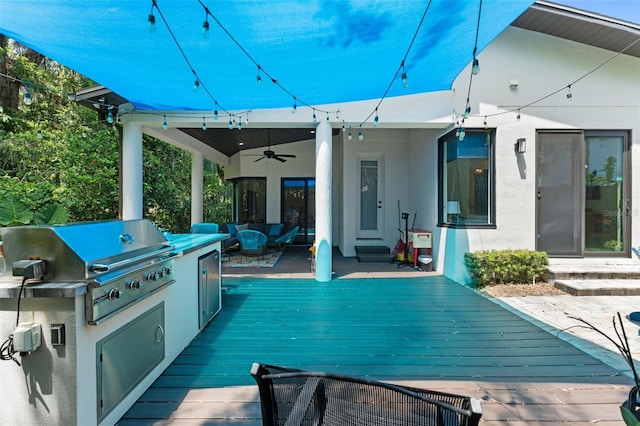 view of patio with area for grilling, exterior kitchen, a ceiling fan, and a wooden deck