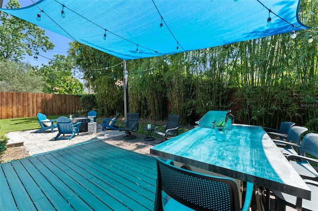 deck featuring a patio, a fire pit, fence, and outdoor dining space