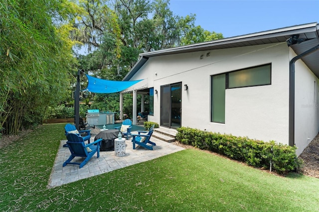 back of house with a lawn, a patio area, and stucco siding