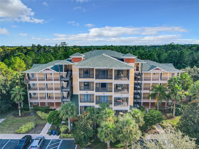 view of property featuring uncovered parking and a view of trees