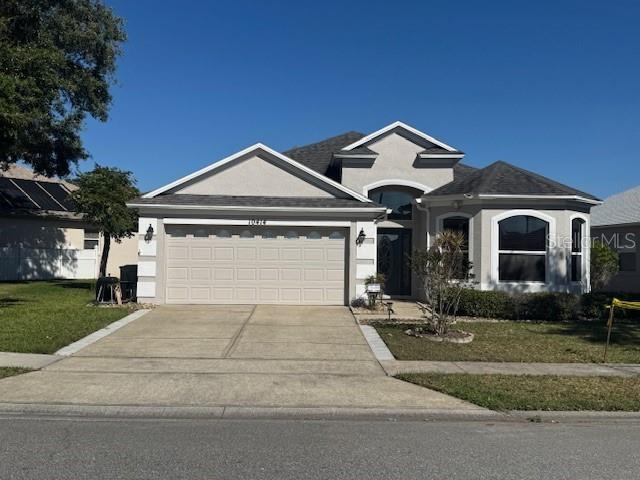 10414 Andover Point Cir, Orlando, FL 32825 - view of front facade with an attached garage, stucco siding, a front yard, and concrete driveway