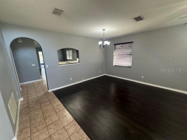 10414 Andover Point Cir, Orlando, FL 32825 - unfurnished room with visible vents, arched walkways, wood finished floors, baseboards, and an inviting chandelier