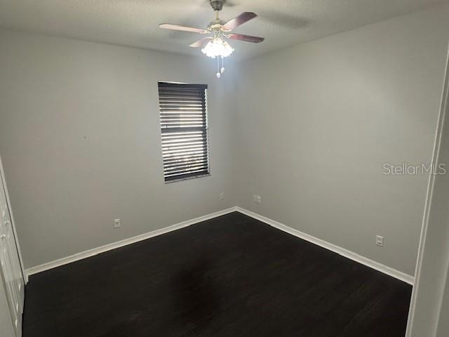 10414 Andover Point Cir, Orlando, FL 32825 - unfurnished room with dark wood-type flooring, a ceiling fan, and baseboards