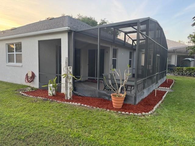 10414 Andover Point Cir, Orlando, FL 32825 - back of house at dusk featuring a shingled roof, a patio, stucco siding, a lanai, and a yard