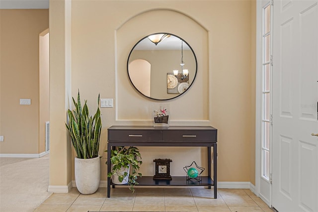 foyer entrance with baseboards, visible vents, light tile patterned floors, and an inviting chandelier