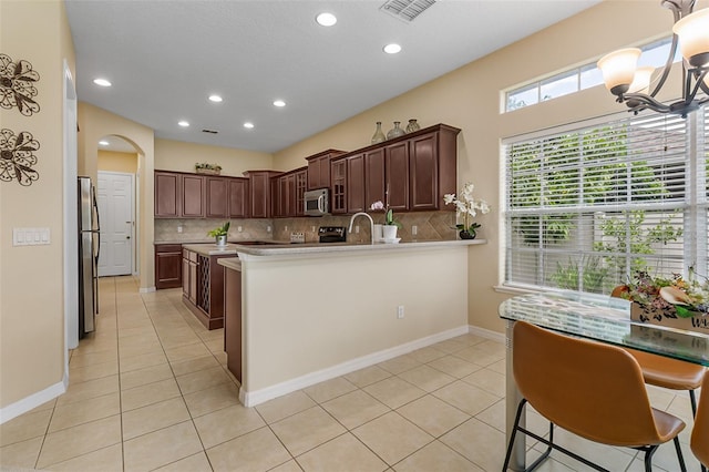 kitchen featuring light tile patterned floors, decorative backsplash, stainless steel appliances, and a sink