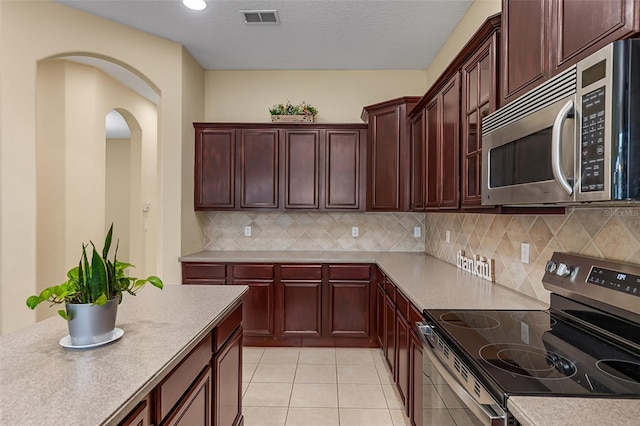 kitchen featuring visible vents, appliances with stainless steel finishes, tasteful backsplash, arched walkways, and light tile patterned floors
