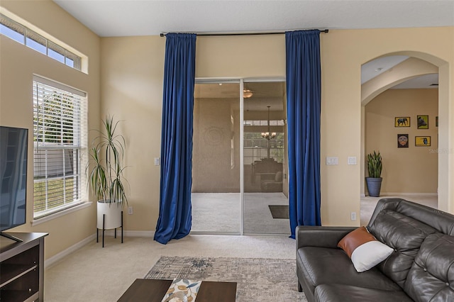 living area featuring baseboards, arched walkways, and carpet flooring