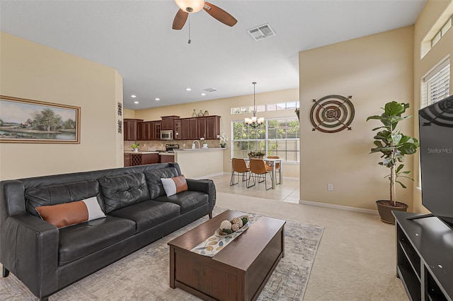 living room featuring baseboards, light carpet, ceiling fan with notable chandelier, and visible vents