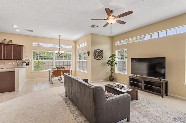 living area featuring visible vents, baseboards, ceiling fan with notable chandelier, and light carpet