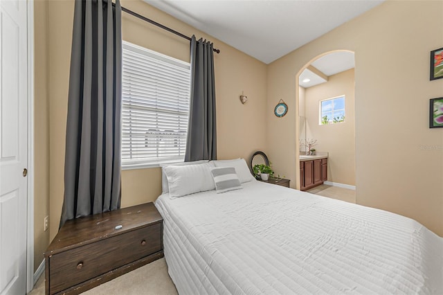 bedroom featuring arched walkways and light carpet