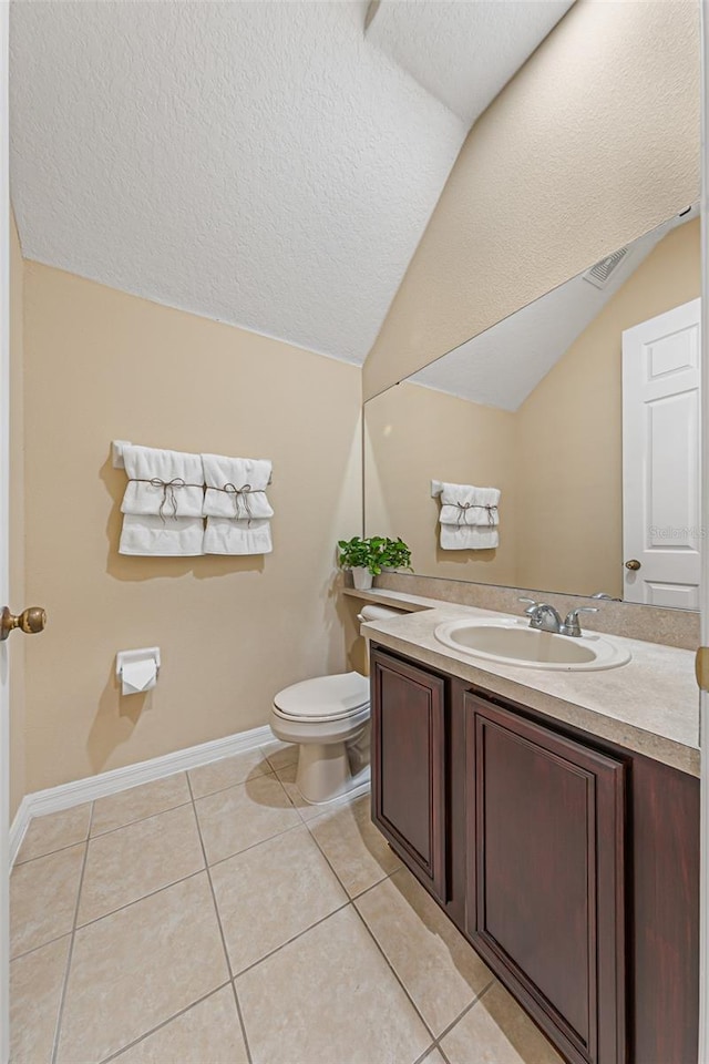 bathroom featuring vanity, lofted ceiling, toilet, baseboards, and tile patterned floors