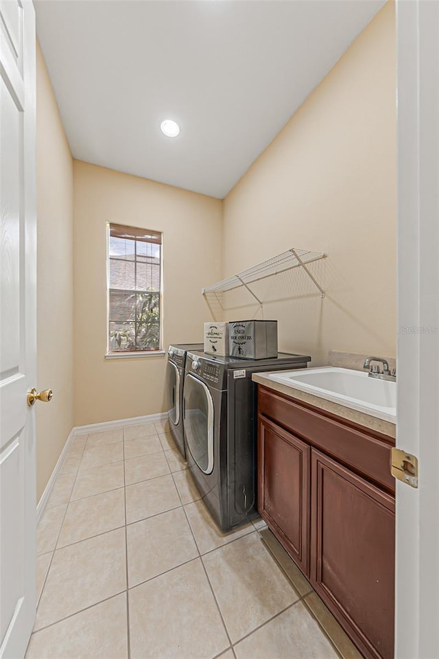 laundry area with washer and dryer, light tile patterned flooring, a sink, and cabinet space
