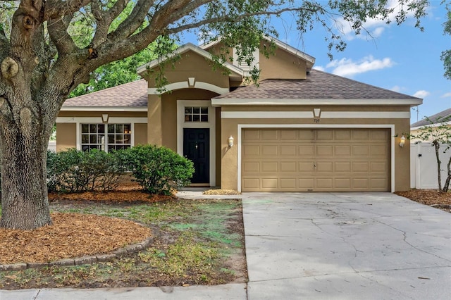 view of front of property with stucco siding, a shingled roof, an attached garage, and driveway