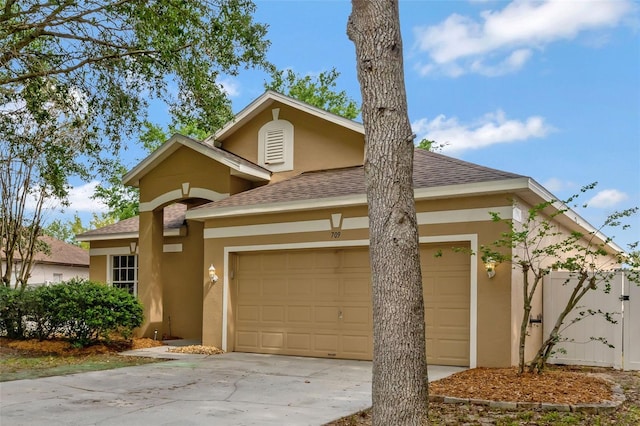 view of front of property with stucco siding, a shingled roof, a garage, and concrete driveway