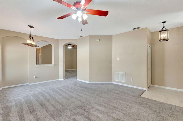 spare room featuring a ceiling fan, carpet flooring, baseboards, and arched walkways