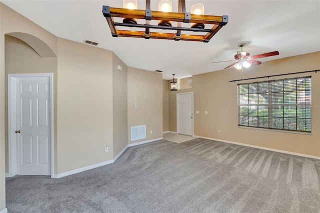 carpeted spare room featuring a chandelier, ceiling fan, and baseboards
