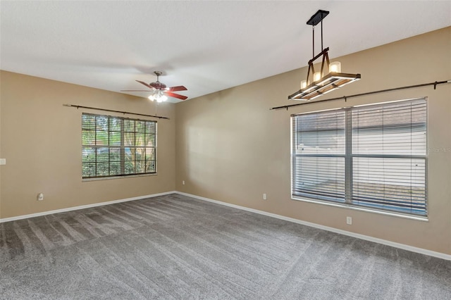 carpeted spare room with ceiling fan and baseboards