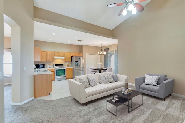 living room featuring light colored carpet, a chandelier, baseboards, ceiling fan, and arched walkways