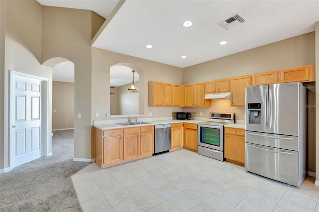 kitchen featuring appliances with stainless steel finishes, under cabinet range hood, a sink, arched walkways, and light countertops
