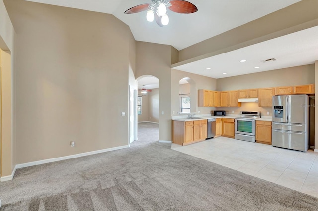 kitchen with stainless steel appliances, ceiling fan, arched walkways, light carpet, and under cabinet range hood