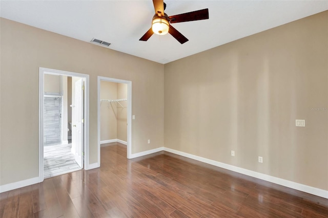 spare room featuring a ceiling fan, dark wood-style floors, and baseboards