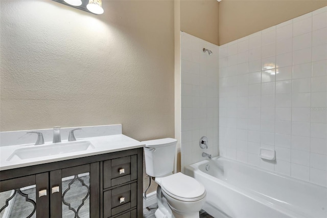 bathroom featuring toilet, tub / shower combination, vanity, and a textured wall