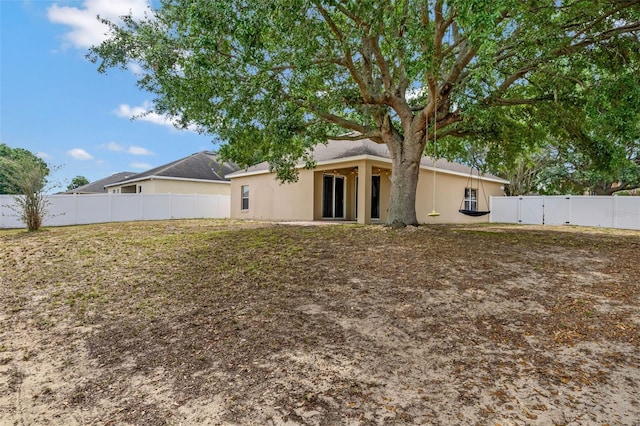 back of house featuring stucco siding, fence, and a gate