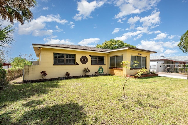 view of front facade featuring fence, concrete block siding, and a front lawn