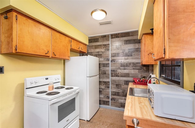 kitchen with wooden walls, brown cabinets, white appliances, light countertops, and visible vents