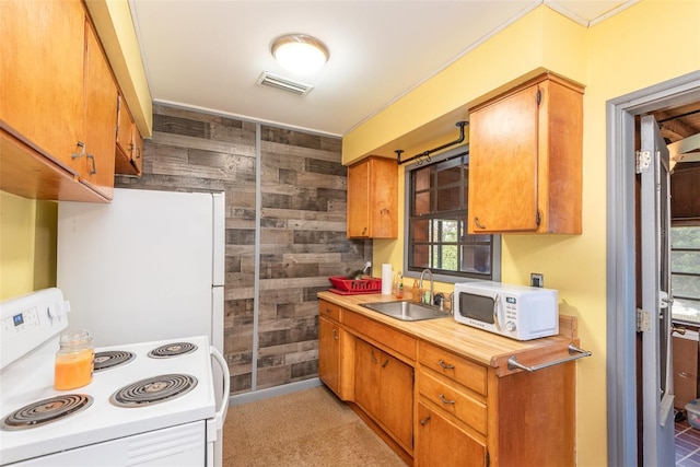 kitchen with visible vents, wood walls, white appliances, light countertops, and a sink