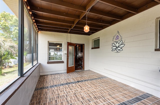 unfurnished sunroom with beam ceiling